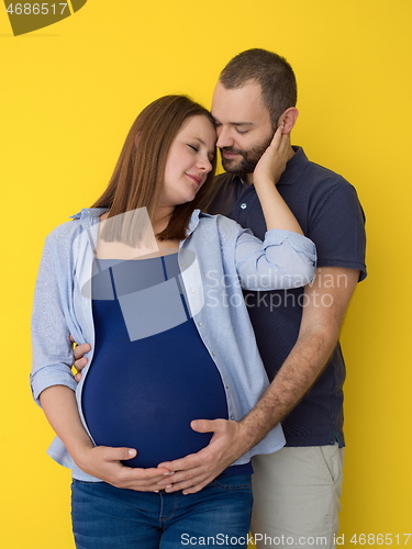 Image of pregnant couple  isolated over yellow background