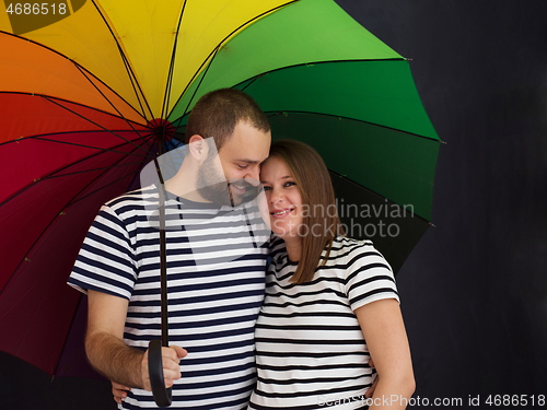 Image of pregnant couple posing with colorful umbrella