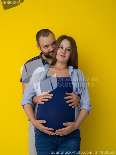 Image of pregnant couple  isolated over yellow background