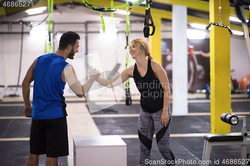 Image of woman working out with personal trainer jumping on fit box