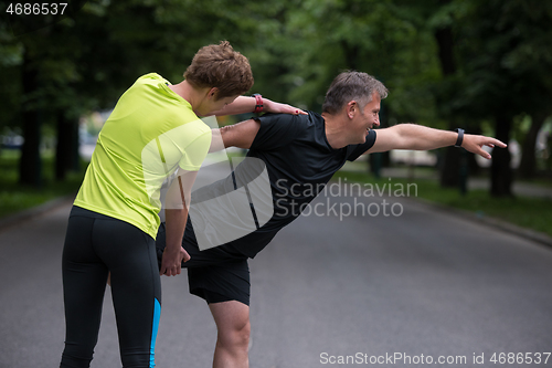 Image of runners team warming up and stretching before morning training