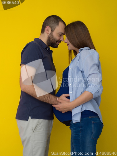 Image of pregnant couple  isolated over yellow background