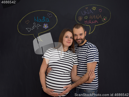 Image of pregnant couple posing against black chalk drawing board