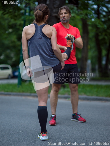 Image of runners team warming up and stretching before morning training