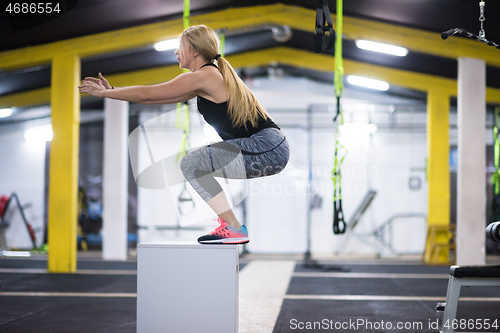 Image of woman working out  jumping on fit box