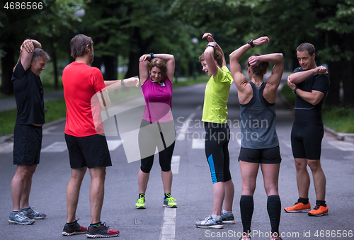 Image of runners team warming up and stretching before morning training