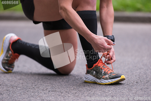 Image of sporty woman tying running shoes laces