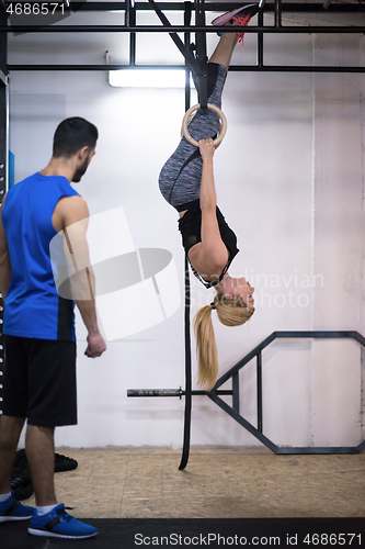 Image of woman working out with personal trainer on gymnastic rings