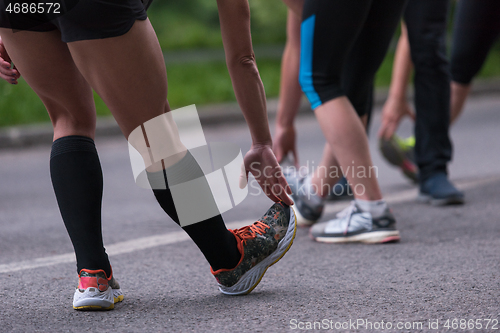 Image of runners team warming up and stretching before morning training