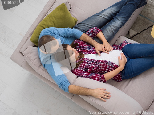 Image of pregnant couple relaxing on sofa