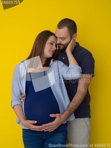 Image of pregnant couple  isolated over yellow background