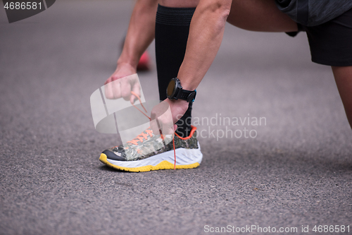 Image of sporty woman tying running shoes laces