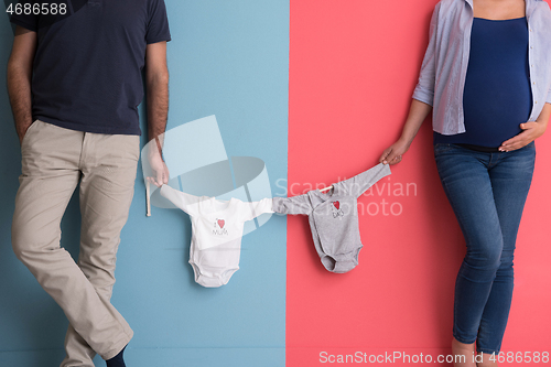 Image of young couple holding baby bodysuits