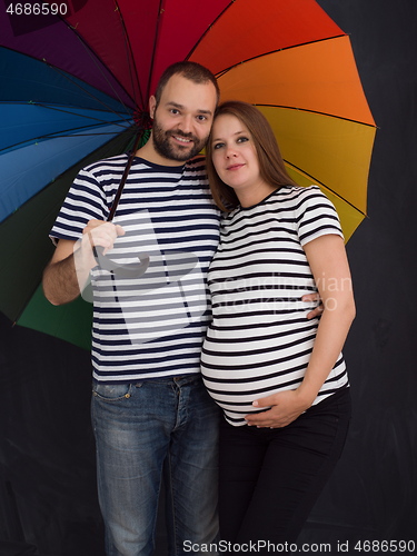 Image of pregnant couple posing with colorful umbrella