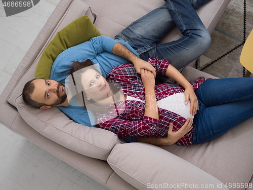 Image of pregnant couple relaxing on sofa