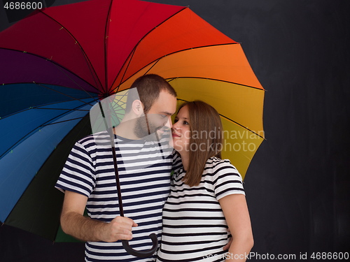 Image of pregnant couple posing with colorful umbrella