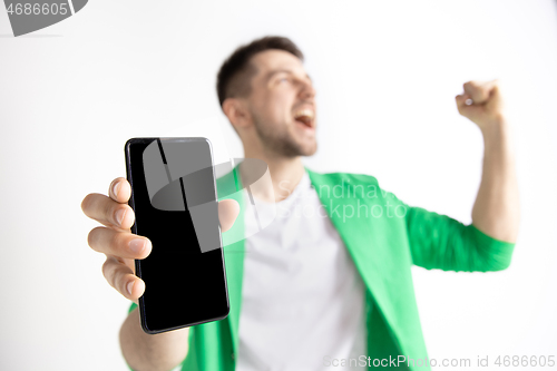 Image of Young handsome man showing smartphone screen and signing OK isolated on gray background