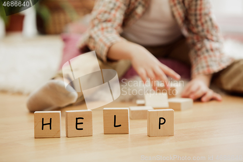 Image of Wooden cubes with word HELP in hands of little boy