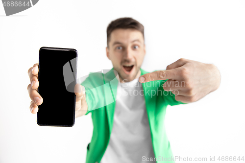 Image of Young handsome man showing smartphone screen and signing OK isolated on gray background