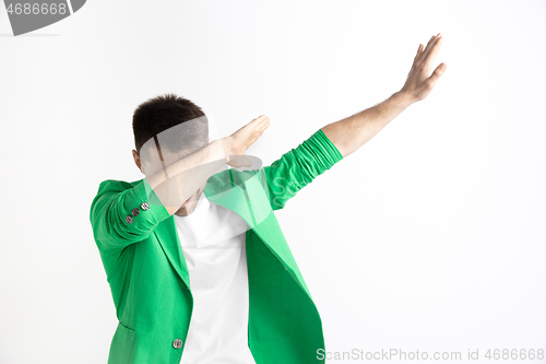 Image of Young man makes the dab movement with his arms on a gray background.