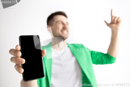 Image of Young handsome man showing smartphone screen and signing OK isolated on gray background