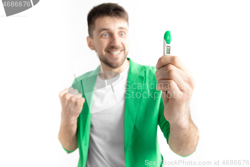 Image of Happy man looking at pregnancy test at studio