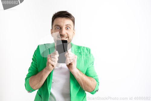 Image of Young handsome man showing smartphone screen and signing OK isolated on gray background