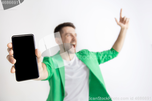 Image of Young handsome man showing smartphone screen and signing OK isolated on gray background