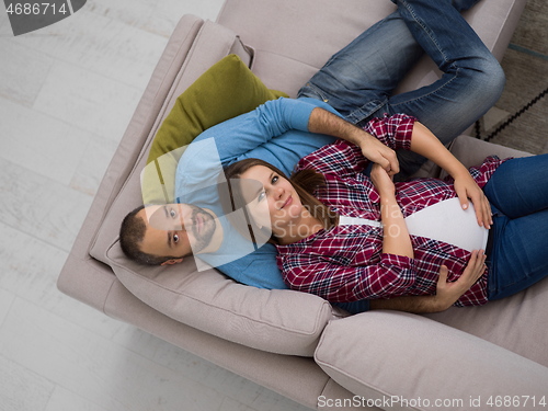 Image of pregnant couple relaxing on sofa