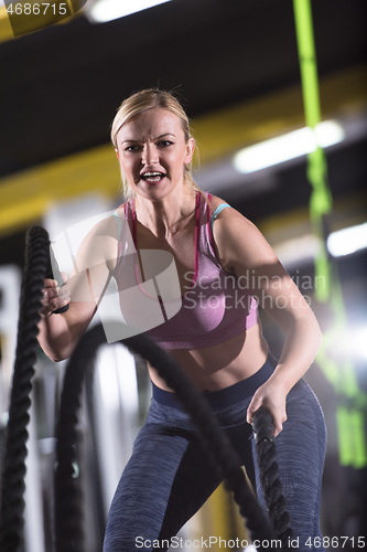 Image of athlete woman doing battle ropes cross fitness exercise