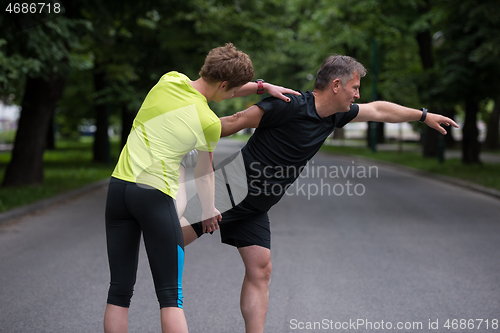 Image of runners team warming up and stretching before morning training