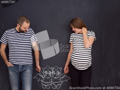 Image of pregnant couple drawing their imaginations on chalk board