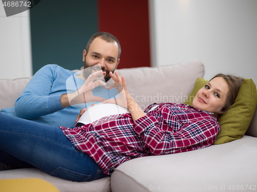 Image of man and pregnant woman showing heart sign