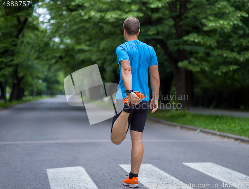 Image of male runner warming up and stretching before morning training