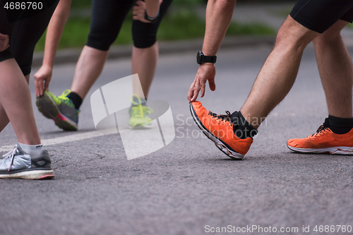 Image of runners team warming up and stretching before morning training