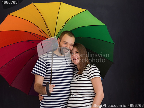 Image of pregnant couple posing with colorful umbrella