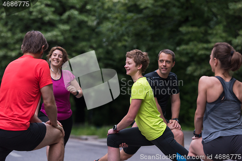 Image of runners team warming up and stretching before morning training