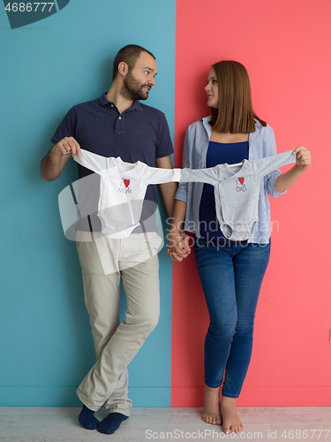 Image of young couple holding baby bodysuits