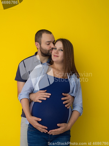 Image of pregnant couple  isolated over yellow background