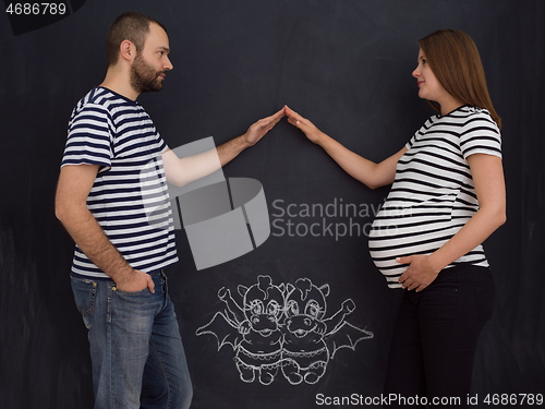 Image of pregnant couple drawing their imaginations on chalk board