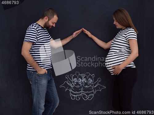 Image of pregnant couple drawing their imaginations on chalk board