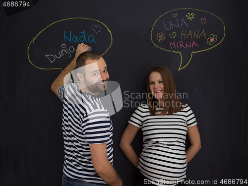 Image of pregnant couple writing on a black chalkboard