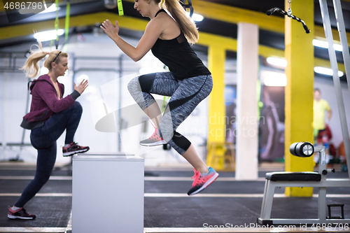 Image of athletes working out  jumping on fit box