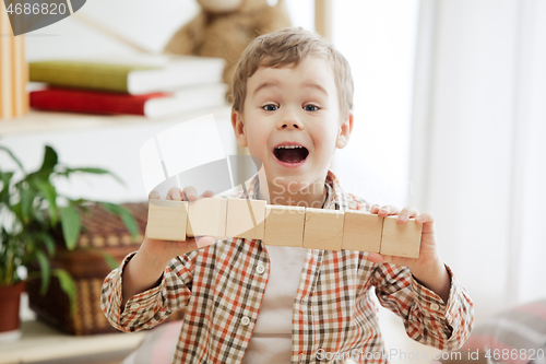 Image of Little child sitting on the floor. Pretty boy palying with wooden cubes at home