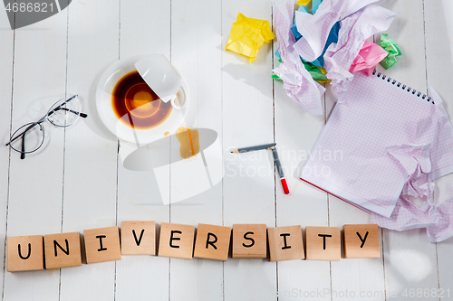 Image of Stationery and word UNIVERSITY made of letters on wooden background