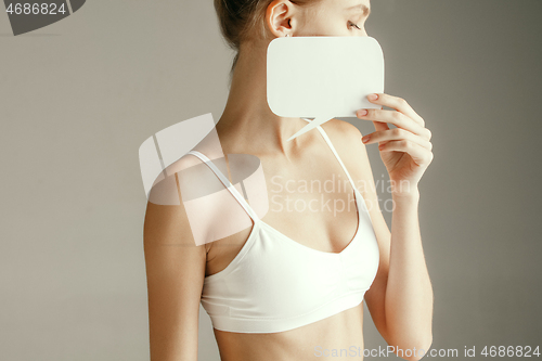 Image of Young adult woman holding empty paper card for sign or symbol.