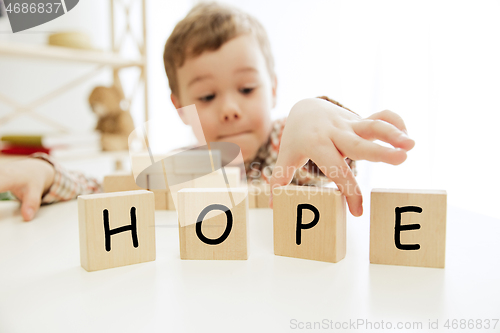 Image of Wooden cubes with word HOPE in hands of little boy