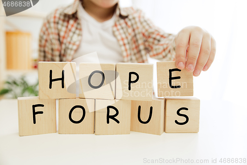 Image of Wooden cubes with words HOPE FOR US hands of little boy
