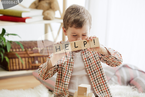 Image of Wooden cubes with word HELP in hands of little boy