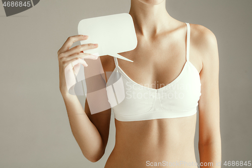 Image of Young adult woman holding empty paper card for sign or symbol.